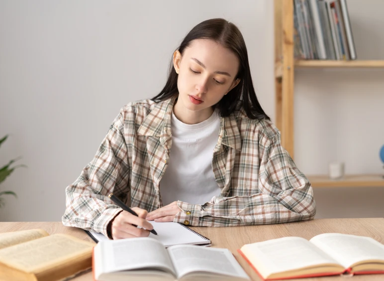 Young student writing notes in a notebook.